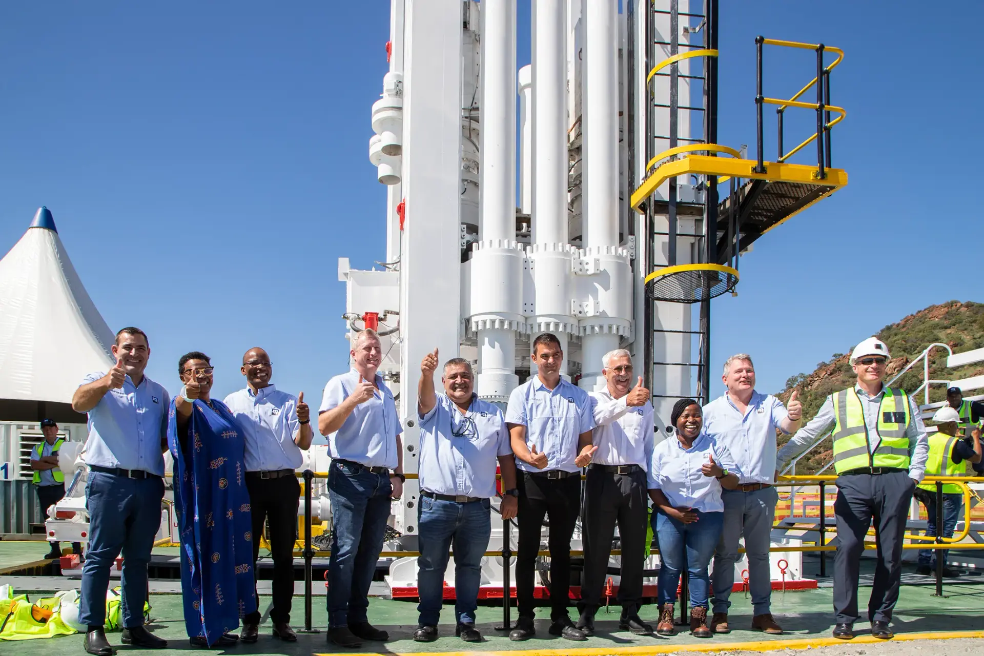 Master Drilling colleagues gathered beside a drilling structure under a clear blue sky.